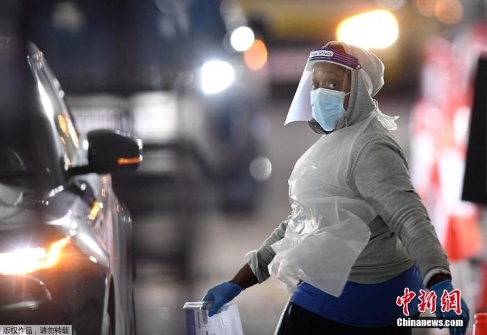 當(dāng)?shù)貢r(shí)間12月18日，英國(guó)政府公布的數(shù)據(jù)顯示，當(dāng)天英國(guó)新增奧密克戎毒株感染病例10059例。鑒于奧密克戎毒株感染病例激增，住院人數(shù)不斷上升，倫敦市長(zhǎng)宣布倫敦進(jìn)入“重大事故”狀態(tài)。圖為倫敦的一個(gè)免下車檢測(cè)中心，一名醫(yī)務(wù)工作者正準(zhǔn)備對(duì)司機(jī)進(jìn)行核酸檢測(cè)。