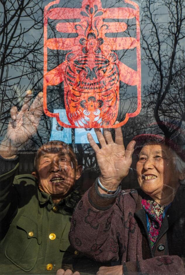 臘月里，霍州市師莊鄉(xiāng)馮南垣村村民師榮光(左)在災(zāi)后重建的新家里貼窗花。(霍州市委宣傳部供圖)