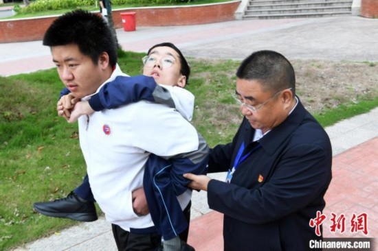 朱金祥背著鐘華強去教室上課的路上，也經(jīng)常碰到值班的校領(lǐng)導(dǎo)和老師前來搭把手。 卓忠偉 攝