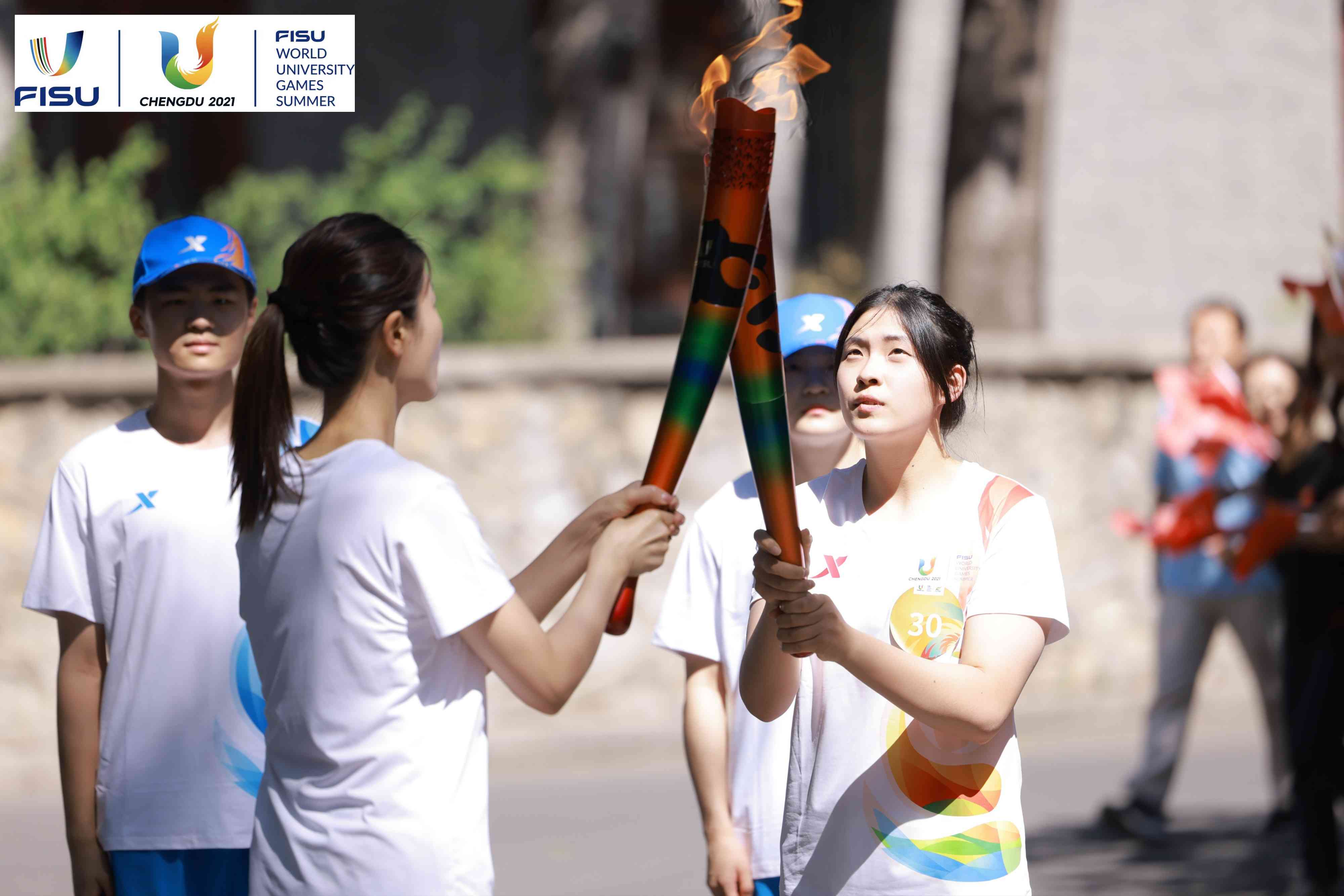 兩名大運(yùn)會火炬手進(jìn)行火炬?zhèn)鬟f。 圖片來源：成都大運(yùn)會執(zhí)委會供圖