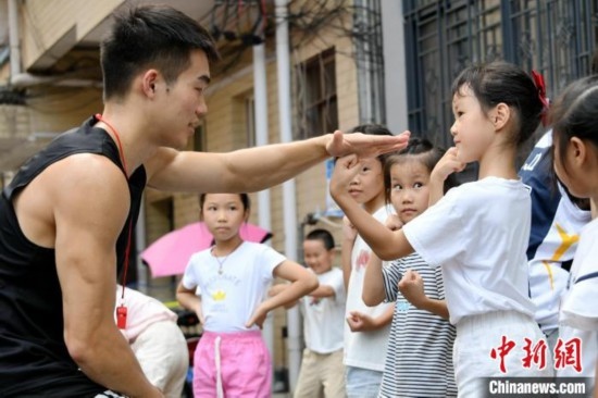 圖為大學(xué)生志愿者在組織孩子們參加體育健身活動。廖光福 攝