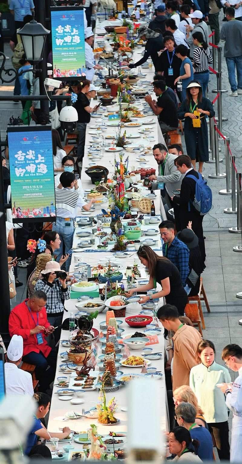 市民和游客在寧波舉辦的第三屆中國(guó)—中東歐國(guó)家博覽會(huì)暨國(guó)際消費(fèi)品博覽會(huì)上品嘗融合中國(guó)和中東歐美食的長(zhǎng)桌宴（2023年5月15日攝）。黃宗治攝/本刊