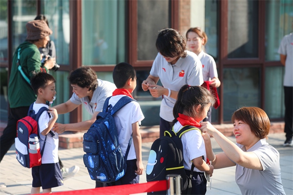 8月30日，雄安史家胡同小學(xué)學(xué)生體驗(yàn)學(xué)校生活。老師為學(xué)生佩戴?；?。