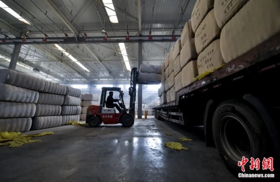 新疆喀什綜合保稅區(qū)，喀什啟路國際貿(mào)易有限公司的倉庫內(nèi)，工人正在裝載從塔吉克斯坦和烏茲別克斯坦進(jìn)口的棉花。劉新攝