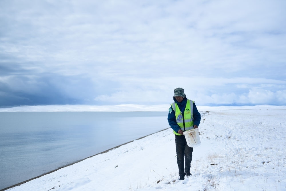 2021年10月20日，在青海省果洛藏族自治州瑪多縣扎陵湖鄉(xiāng)勒那村，三江源國(guó)家公園黃河源園區(qū)生態(tài)管護(hù)員在扎陵湖邊撿拾垃圾。新華社記者 張龍 攝