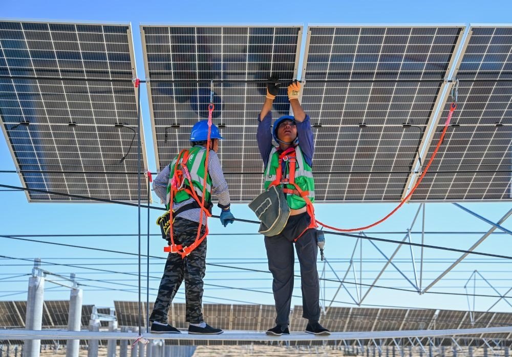 2023年7月22日，工人在位于內(nèi)蒙古杭錦旗庫布其沙漠億利生態(tài)示范區(qū)的蒙西基地庫布其200萬千瓦光伏治沙項(xiàng)目工地安裝光伏板。新華社記者 劉磊 攝