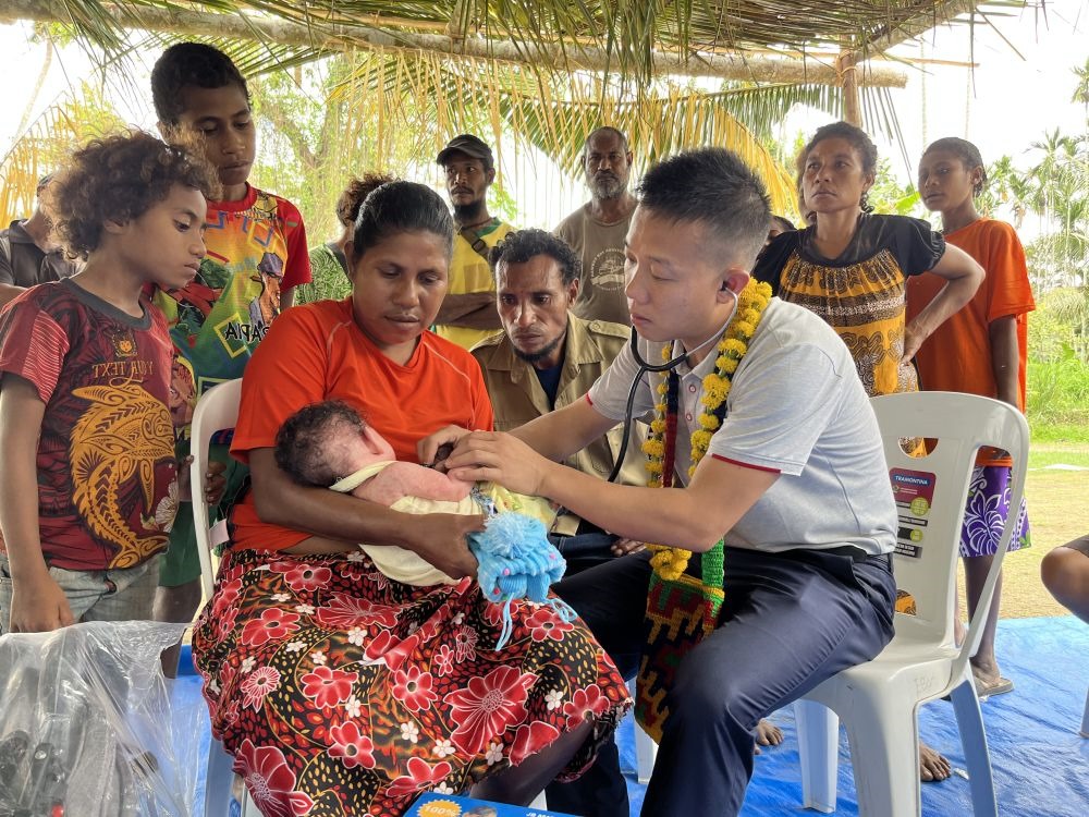 2023年8月5日，在巴布亞新幾內(nèi)亞中央省的一個村莊里，第12批援巴新中國醫(yī)療隊副隊長、新生兒科副主任醫(yī)師劉振球為嬰兒泰樂聽診檢查。泰樂出生時患有重癥，一度生命垂危，經(jīng)過劉振球與當(dāng)?shù)蒯t(yī)護(hù)人員的救治最終痊愈。從2002年起，中國連續(xù)向巴新派出12批醫(yī)療隊，為提高巴新醫(yī)療衛(wèi)生水平作出積極貢獻(xiàn)。