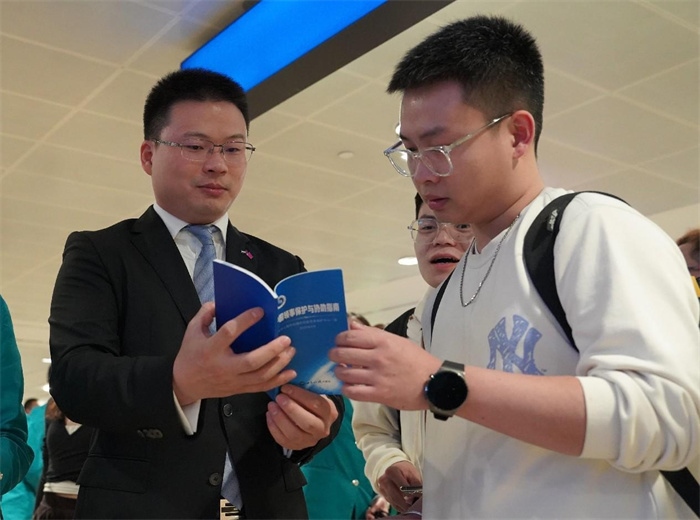 工作人員（左一）在發(fā)放《中國領事保護與協(xié)助指南》。 中國駐迪拜總領事館供圖