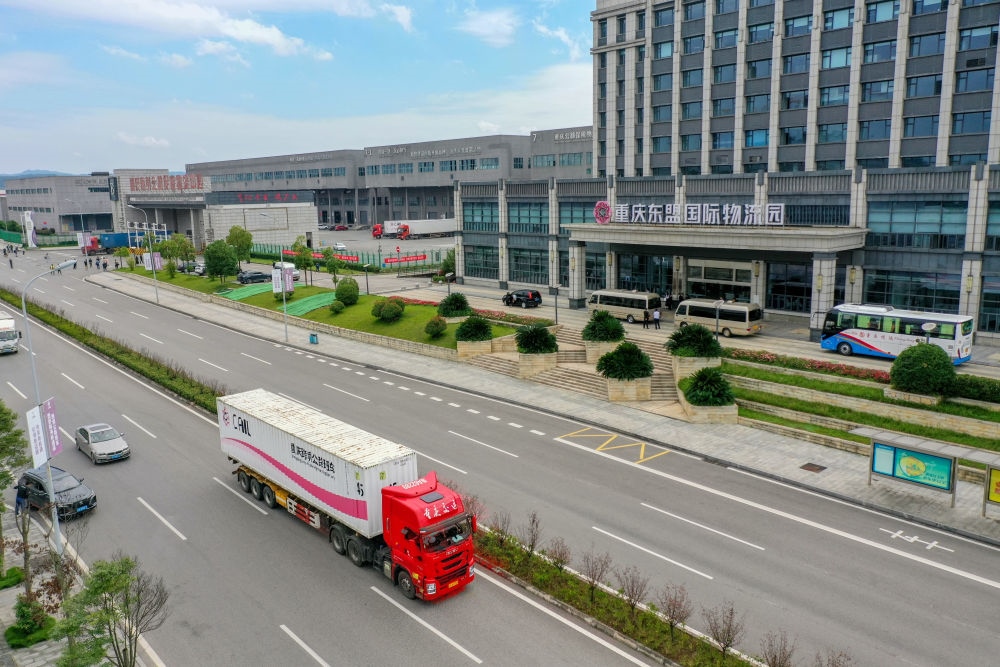 2023年10月11日，滿(mǎn)載筆記本電腦配件、發(fā)電機(jī)組件等產(chǎn)品的西部陸海新通道跨境公路班車(chē)從重慶南彭公路保稅物流中心駛出，將途經(jīng)廣西憑祥，直達(dá)越南（無(wú)人機(jī)照片）。新華社記者 黃偉 攝