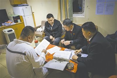 圖②：法官向船長講解相關(guān)法律規(guī)定，查看船舶資料，并與船方辦理扣押船舶的手續(xù)。