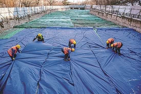 1月3日，房山區(qū)東風(fēng)街道，工人正在修復(fù)的河道內(nèi)給混凝土鋪設(shè)保溫布。