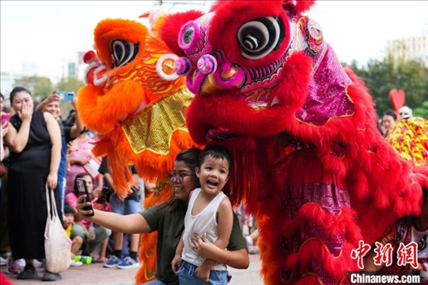 圖為舞獅表演吸引民眾合影。張興龍攝