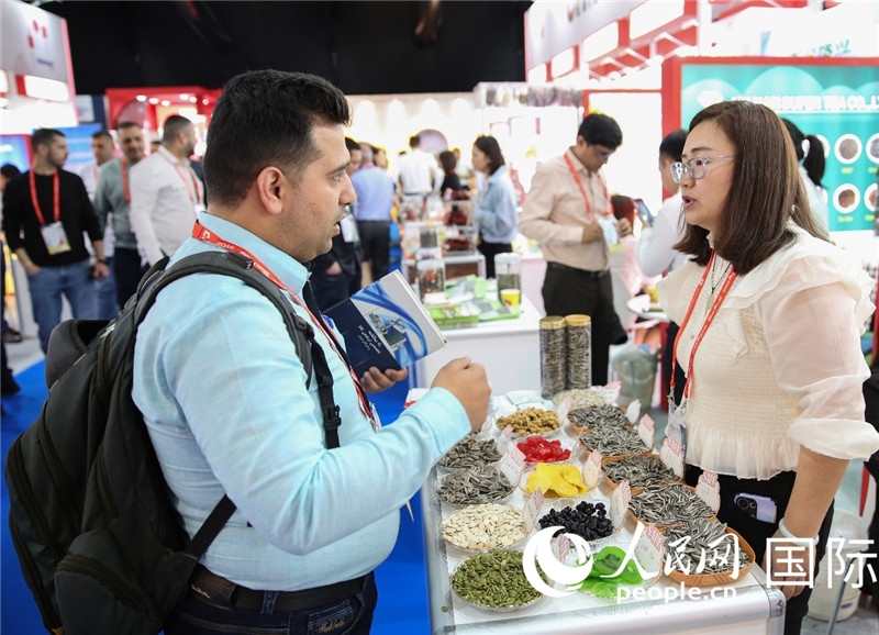 圖為一家中國干果參展企業(yè)代表與采購商洽談。人民網(wǎng) 塔里克·易卜拉欣攝