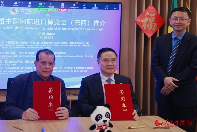 巴西外貿(mào)商會聯(lián)合會會長阿代爾·羅伯托（左）與中國國際進(jìn)口博覽局副局長吳政平（中）現(xiàn)場簽訂協(xié)議。人民網(wǎng)記者 宋亦然攝