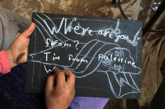 2023年12月28日，一名學(xué)生在加沙地帶南部城市拉法一所學(xué)校的臨時(shí)教室中寫(xiě)下“我來(lái)自巴勒斯坦”的字樣。新華社發(fā)（里澤克·阿卜杜勒賈瓦德攝）