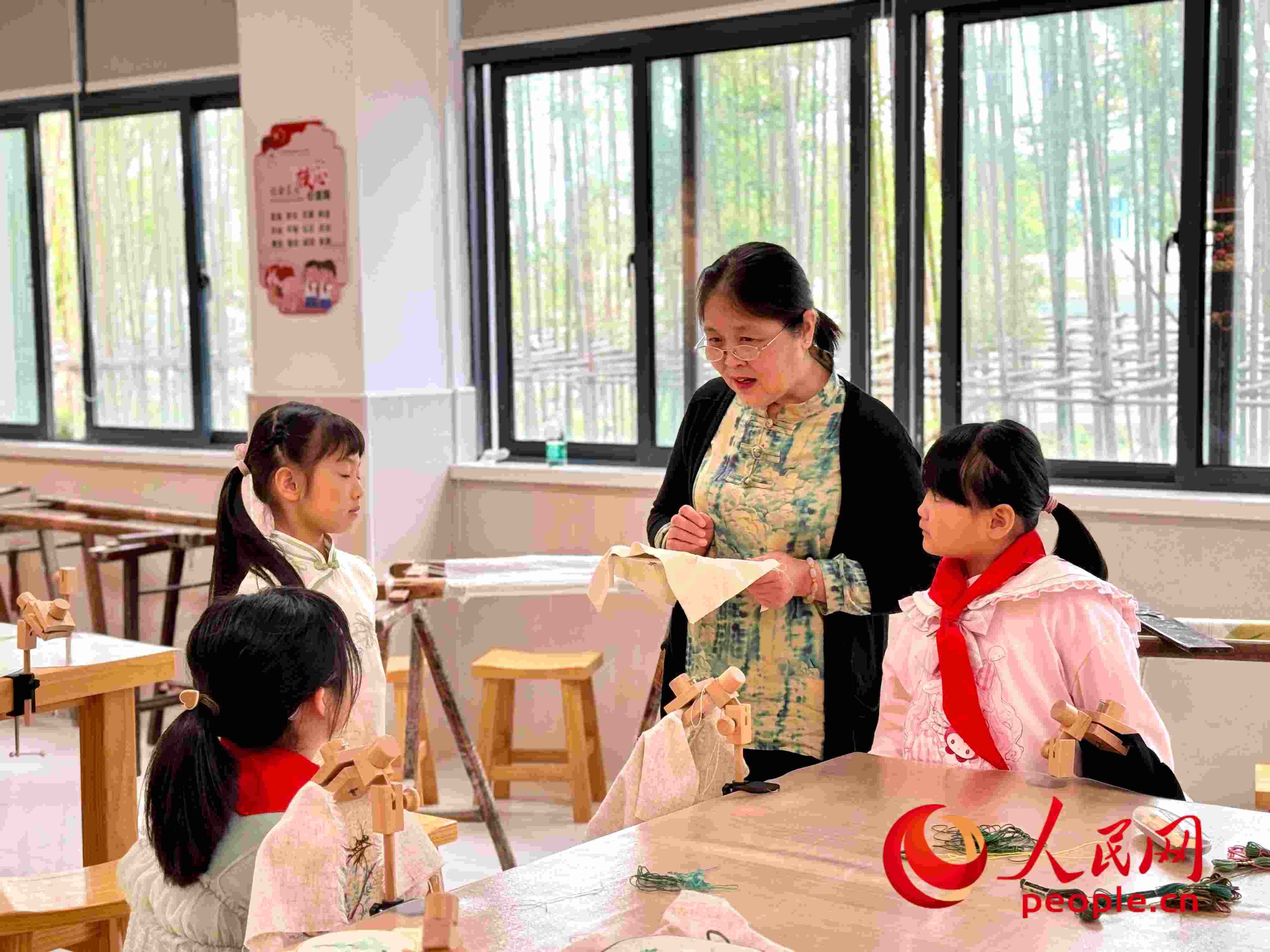 顧建珍（左三）在教孩子們刺繡知識(shí)。人民網(wǎng) 周靜圓攝