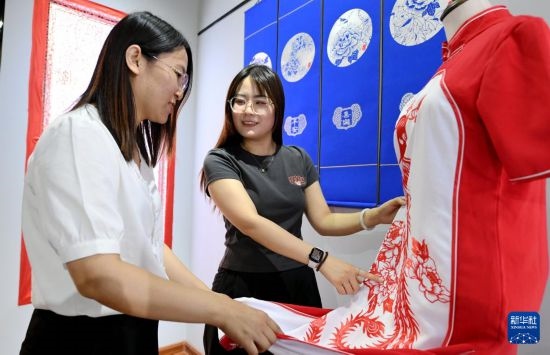 5月31日，在衡水市阜城縣一家剪紙工作室，游客在觀賞帶有剪紙?jiān)氐钠炫邸? width=