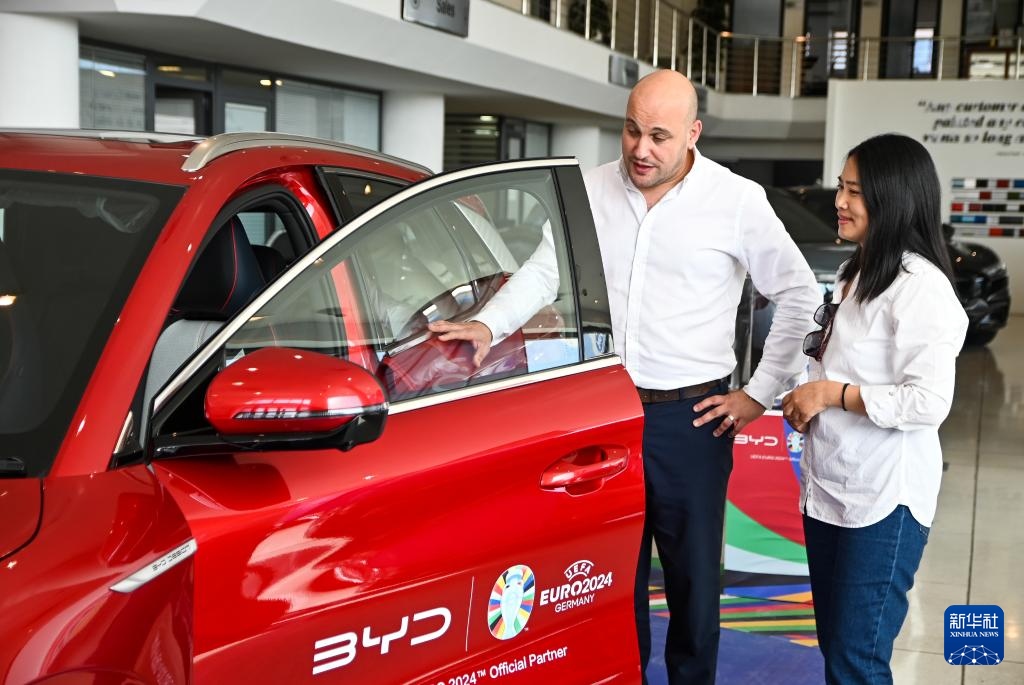 2024年5月29日，在馬耳他比爾基卡拉，馬耳他哈桑-扎米特汽車公司首席執(zhí)行官德古阿拉（左）介紹一輛比亞迪純電動汽車。新華社發(fā)（喬納森·博格 攝）