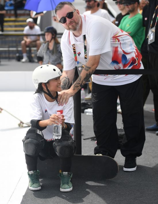 6月20日，鄭好好（左）在比賽間隙與教練互動，她在預賽中最佳成績?yōu)?2.60分。當日，巴黎奧運會資格系列賽布達佩斯站滑板女子碗池預賽在布達佩斯舉行。新華社記者 賀燦鈴 攝