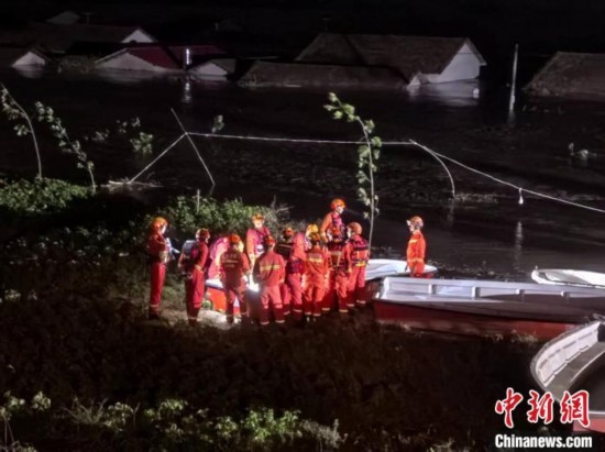  7月6日凌晨3時，在湖南岳陽華容縣團(tuán)洲垸洞庭湖一線堤防，救援人員剛剛完成一次救援任務(wù)，遠(yuǎn)處是被淹的民房。中新社記者 白祖偕 攝