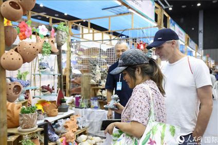 游客在蘭納博覽會特色展位上選購工藝品。人民網(wǎng)記者楊一攝