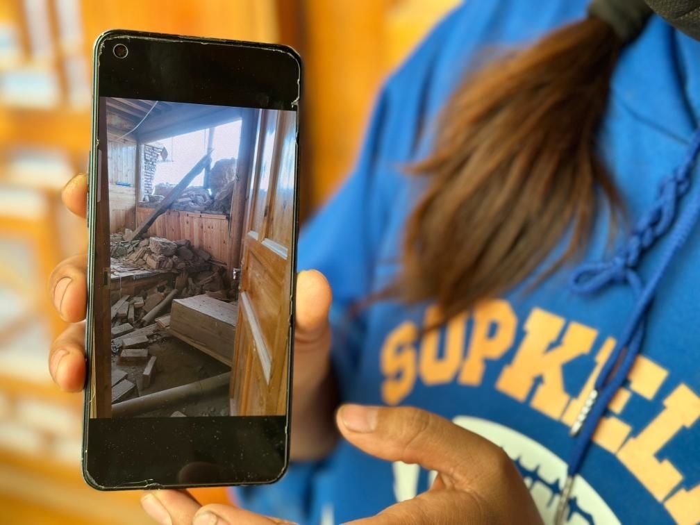 圖為7月17日拉毛東智在手機上找出地震后房屋受損的照片。新華社記者 張子琪 攝