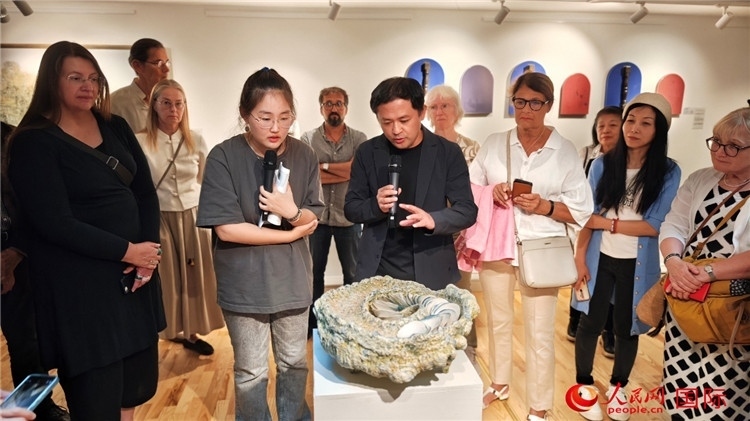 參展人、景德鎮(zhèn)陶瓷大學(xué)設(shè)計(jì)藝術(shù)學(xué)院副院長(zhǎng)余劍峰（中）向來(lái)賓介紹參展作品。人民網(wǎng)記者 殷淼攝