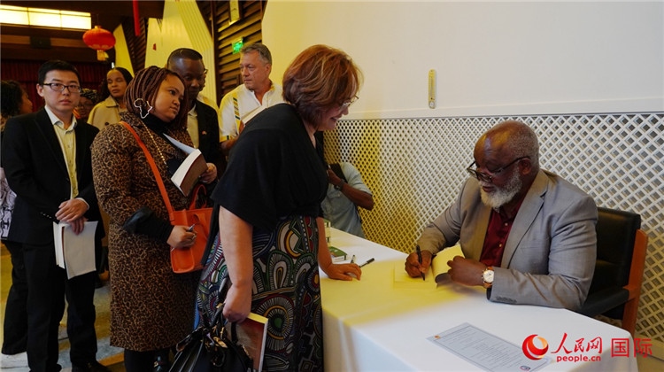 譚哲理在活動現(xiàn)場簽名贈書。人民網(wǎng) 劉暢攝