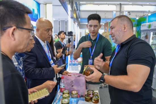2023年8月23日，在第十四屆中國—東北亞博覽會(huì)東北亞商品館，俄羅斯參展商向參觀者介紹商品。