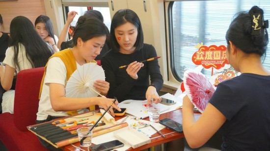 10月1日，旅客們在G1634次列車上給油紙傘作畫。新華社記者周義 攝