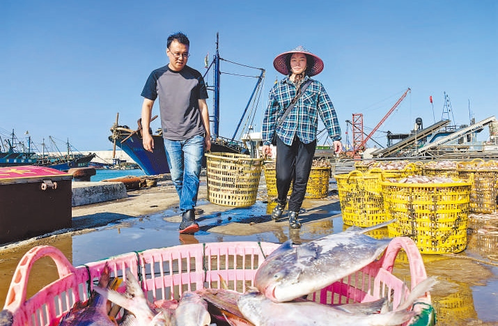 許小斌（左）和漁民一起搬運(yùn)海鮮。本報(bào)記者 付 文攝