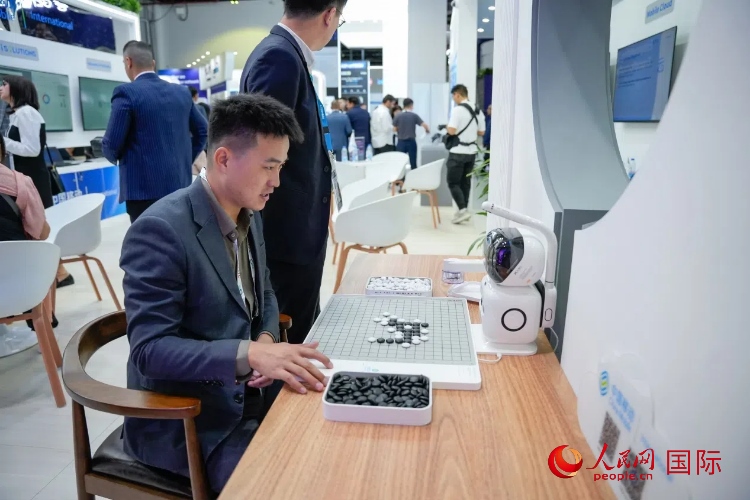 觀眾在中國移動(dòng)國際有限公司展臺(tái)體驗(yàn)智慧圍棋機(jī)器人。人民網(wǎng) 塔里克·易卜拉欣攝
