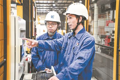 在廣西柳工機械股份有限公司生產車間內，一名高級技師（右）給徒弟講解數控設備操作細節(jié)。新華社記者 曹祎銘攝