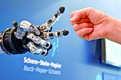 在德國漢諾威工博會上，參觀者與一款智能機器人進行“石頭剪子布”游戲。新華社發(fā)