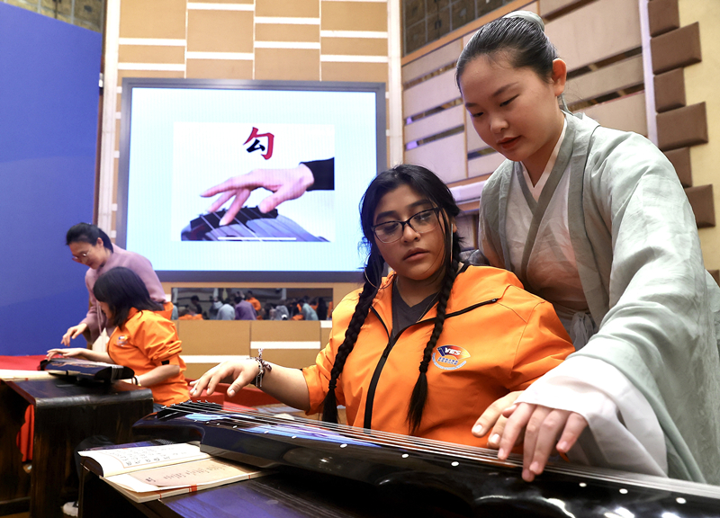 2024年3月20日，美國華盛頓州中學(xué)生代表團(tuán)北京大學(xué)交流活動(dòng)在北京大學(xué)英杰交流中心舉行。圖為來自華盛頓州的中學(xué)生體驗(yàn)古琴。