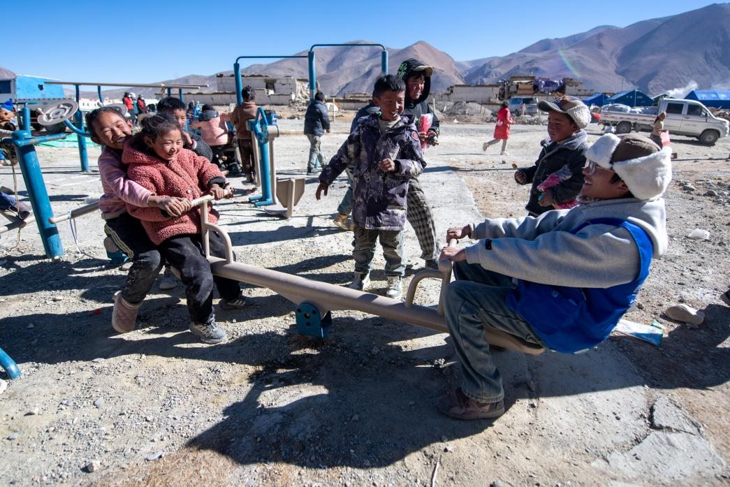 1月11日，在定日縣措果鄉(xiāng)塘仁村安置點，西藏星光社會工作服務(wù)中心志愿者和孩子們一起玩耍，進行災(zāi)后心理疏導(dǎo)。人民網(wǎng)記者 翁奇羽攝