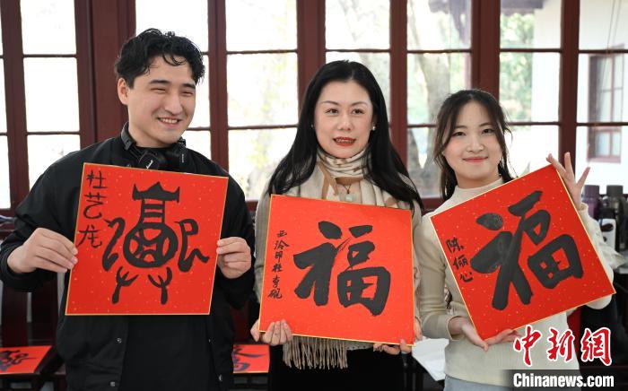 1月20日，外籍留學(xué)生和西泠印社社員李硯(中)展示各自創(chuàng)作的福貼。當(dāng)日，來自巴西、馬來西亞、加納、哈薩克斯坦的外籍留學(xué)生在浙江杭州西泠印社體驗(yàn)福貼、春聯(lián)和篆刻，感受古老的中國傳統(tǒng)文化。中新社記者 王剛 攝