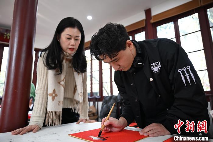 1月20日，外籍留學(xué)生在西泠印社社員李硯指導(dǎo)下寫福。當(dāng)日，來自巴西、馬來西亞、加納、哈薩克斯坦的外籍留學(xué)生在浙江杭州西泠印社體驗(yàn)福貼、春聯(lián)和篆刻，感受古老的中國傳統(tǒng)文化。中新社記者 王剛 攝