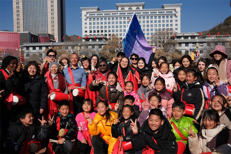 中外青年學(xué)子在安塞文化廣場(chǎng)觀看陜北腰鼓和大秧歌表演后合影留念，大家踏著鼓點(diǎn)共舞，翻飛的紅綢與躍動(dòng)的身影交織，在黃土地廣場(chǎng)上繪出一幅生動(dòng)的陜北民俗互動(dòng)畫卷