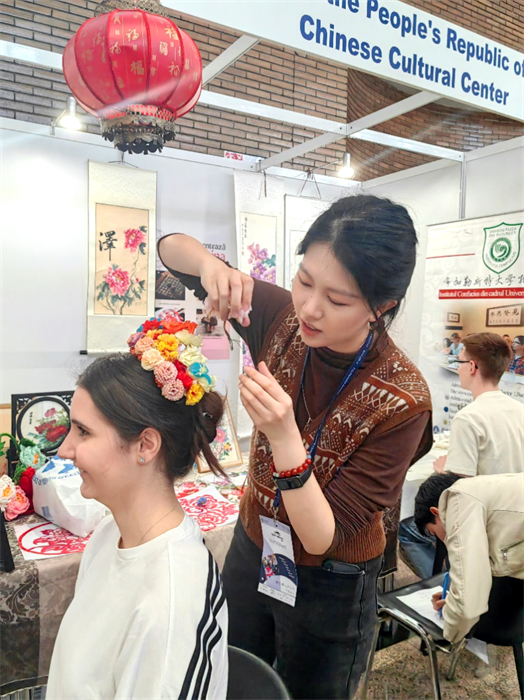 展覽正值羅馬尼亞迎春花節(jié)，國際中文教師志愿者潘婧穎向游客們介紹了國家非物質(zhì)文化遺產(chǎn)——福建泉州的簪花文化。布加勒斯特大學孔子學院供圖。