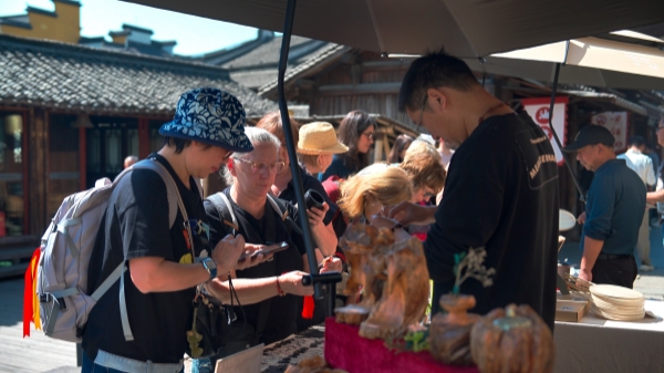 “五一”期間，游客正在烏鎮(zhèn)“水鄉(xiāng)碼頭”挑選購買文創(chuàng)產(chǎn)品。受訪者供圖